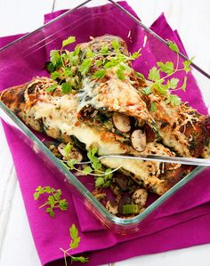 a glass dish filled with food on top of a purple napkin next to a fork