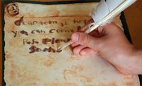 a person writing on an old parchment paper with a feather quill and ink pen