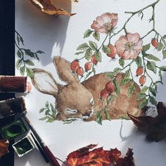 a painting of a rabbit surrounded by leaves and flowers on a sheet of white paper