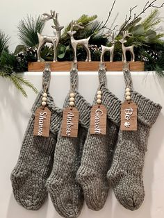 four christmas stockings hanging on a rack with wooden tags and reindeer figurines in the background