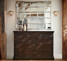 a dresser and mirror in a room with wood flooring, white walls and wooden beams