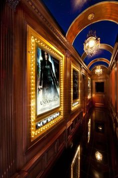 a hallway with lights and posters on the walls, along with chandeliers hanging from the ceiling