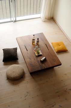 a wooden table sitting on top of a hard wood floor next to two bottles of alcohol