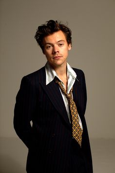 a young man in a suit and tie posing for a photo with his hands on his hips