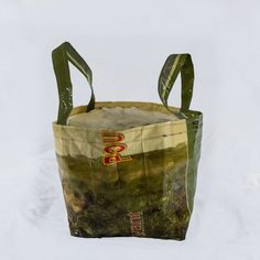 a bag that is sitting on the ground with some grass in front of it and trees behind it