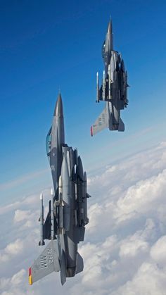 two fighter jets flying in the sky above clouds