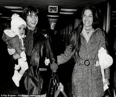 black and white photograph of two people holding their baby's hand while walking through an airport