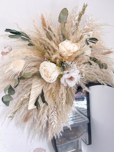 a vase with flowers and feathers hanging on the wall next to a mirror in a room