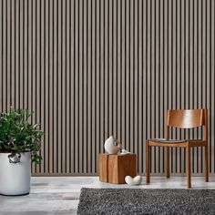 a chair, vase and potted plant in front of a wall with vertical stripes