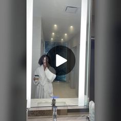 a woman taking a selfie in front of a bathroom mirror while brushing her teeth