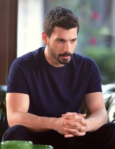 a man sitting on a couch with his hands folded