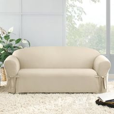 a white couch sitting on top of a shaggy rug next to a vase filled with flowers