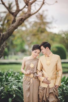 a man and woman standing next to each other in front of a tree with flowers