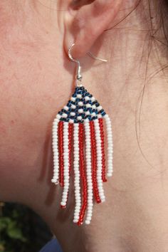 a woman wearing red, white and blue beaded earrings with an american flag design