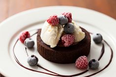 a chocolate dessert topped with whipped cream and raspberries on top of a white plate