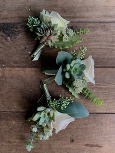 three white roses and greenery on a wooden surface