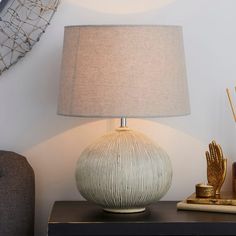 a lamp sitting on top of a wooden table next to a book and other items