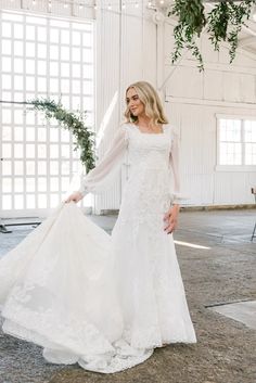 a woman in a white wedding dress is posing for the camera with her long sleeves on