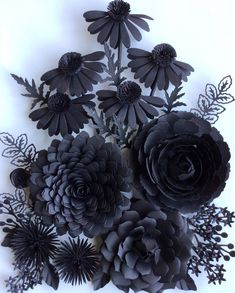 black paper flowers are arranged on a white surface