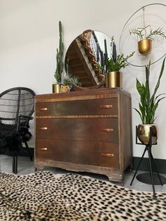 a room with a dresser, chair and mirror on the wall next to a leopard print rug