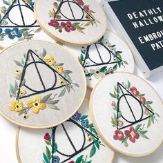 four embroidered harry potter coasters sitting on top of a table next to a book