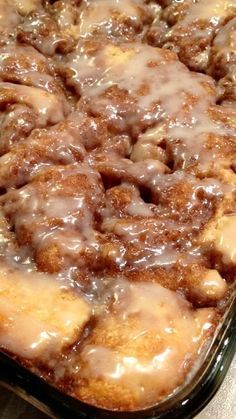 a close up of a cake in a pan with icing and cinnamon rolls on top