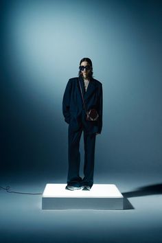 a man in a suit and sunglasses standing on top of a white box with a string attached to it