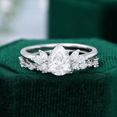 a diamond ring sitting on top of a green velvet cushioned surface with three diamonds surrounding it