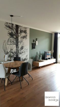 a living room with wood flooring and a tree painted on the wall behind it