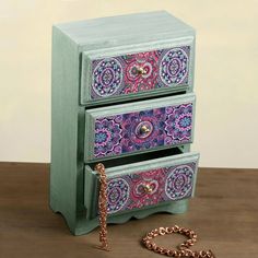 two drawers with colorful designs on them and a chain hanging from the bottom, sitting on a table