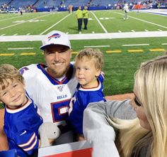 a man and two young boys are posing for a photo at a football game with their parents