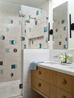 a bathroom with blue and white tiles on the wall, sink and shower stall area