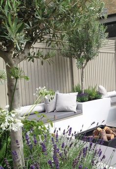 an outdoor living area with white couches and purple flowers