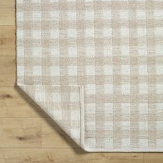 a beige and white checkered rug on top of a wooden floor