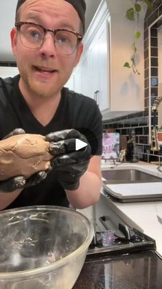 a man in black shirt holding up a glove next to a bowl with food on it