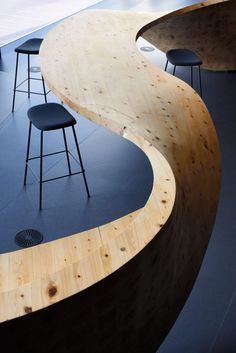 three stools sitting next to each other near a wooden table and counter top in a room