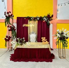 a table is set up with red and white flowers, gold decorations, and a chair