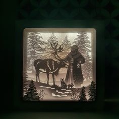 a paper cut depicting a man and his dog in the snow with trees behind him