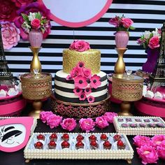 a table topped with cakes and desserts covered in pink flowers next to the eiffel tower