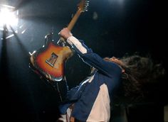 a man with his arms in the air while playing an electric guitar at a concert