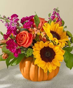 a vase filled with lots of colorful flowers sitting on top of a white table next to a wall