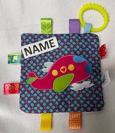 a name tag with a pink dinosaur on it and some colorful clips attached to it