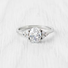 a diamond ring with three stones on the side and an oval center stone in the middle