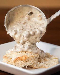 a spoon scooping some food out of a white square dish on a wooden table