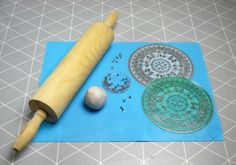 a wooden rolling pin next to some cutouts on a blue mat