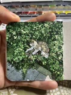 a person holding up a small book with a cat on it's front cover