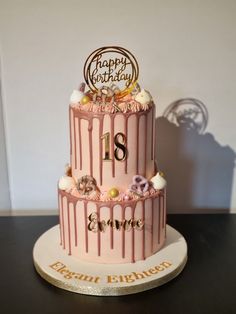 a three tiered cake with pink icing and gold decorations