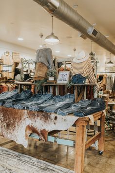 several pairs of jeans are on display in a clothing store with cow hide rugs