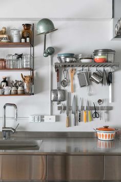 a kitchen with stainless steel counter tops and shelves filled with utensils, pans, and pots