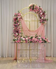 a pink and gold wedding arch decorated with flowers